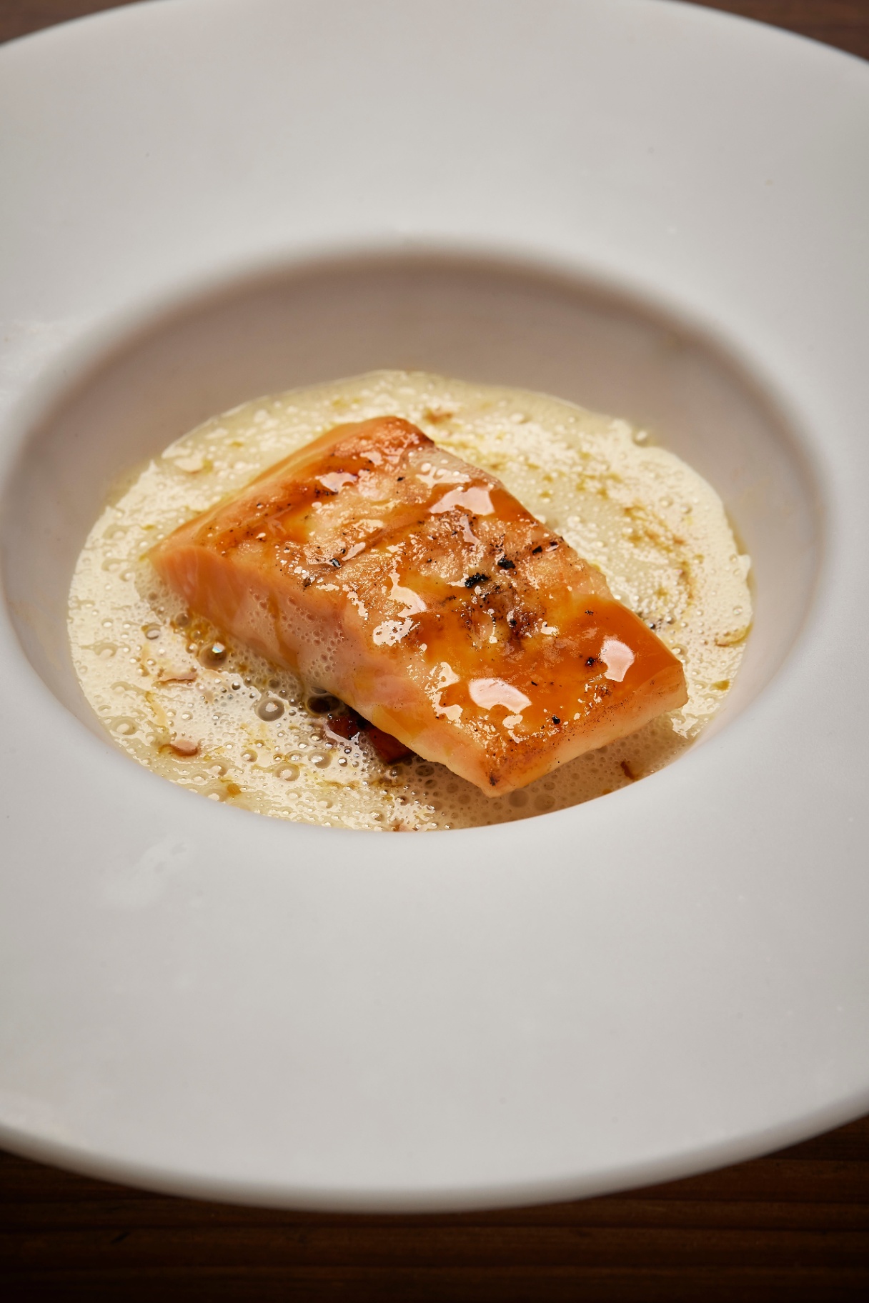 Grillet laks serveret i cremet sauce i dyb tallerken