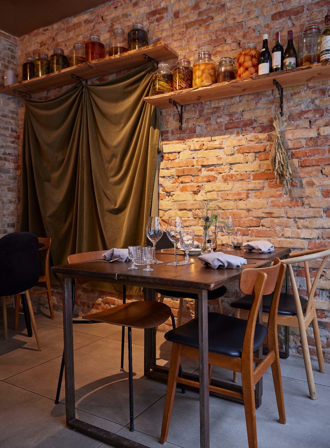 Bord i spisesalen på Restaurant Grim med vinglas, træmøbler og krukker på murstensvæggen