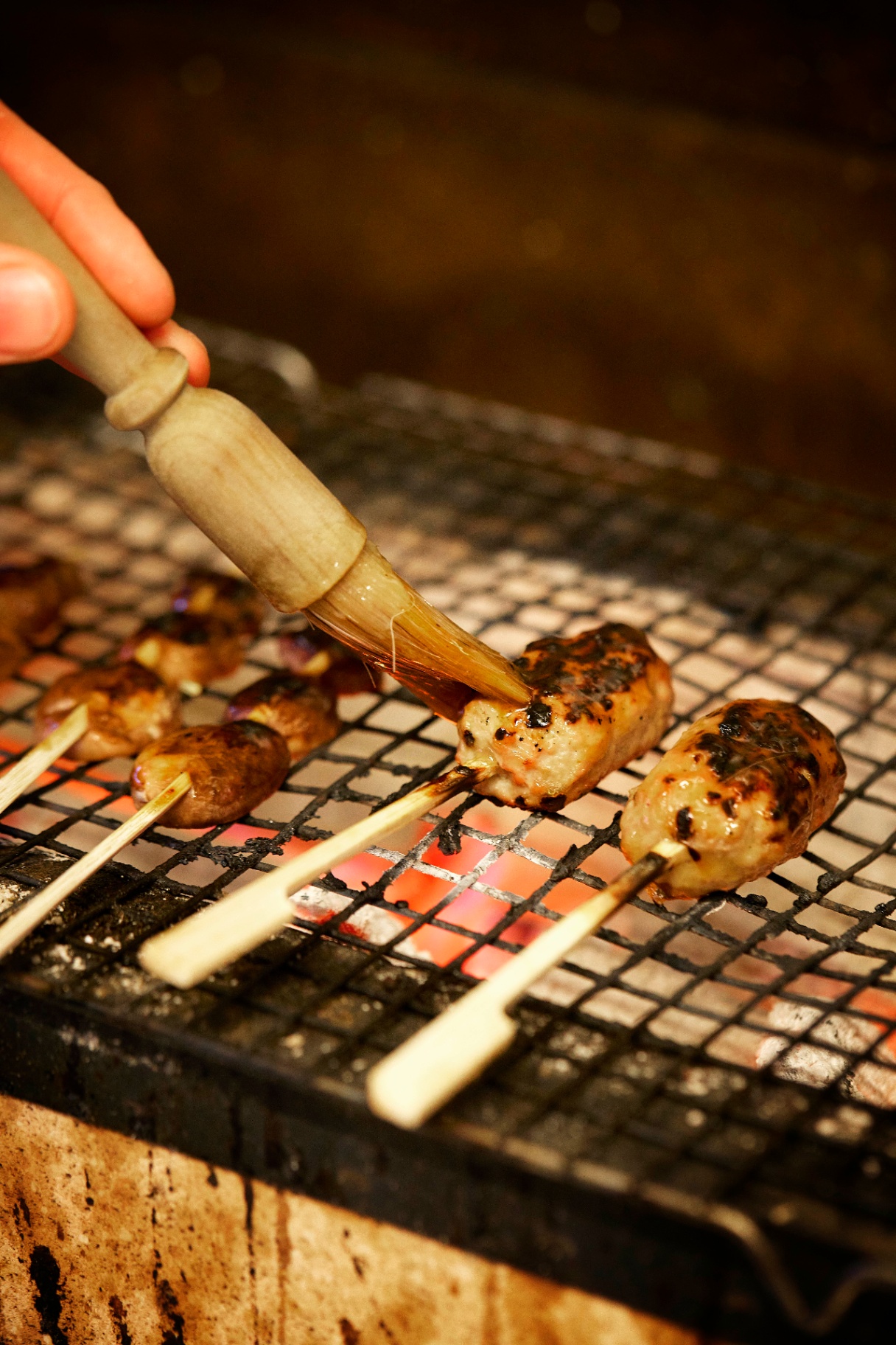 Yakitori-spyd grilles over glødende trækul i Restaurant Grim