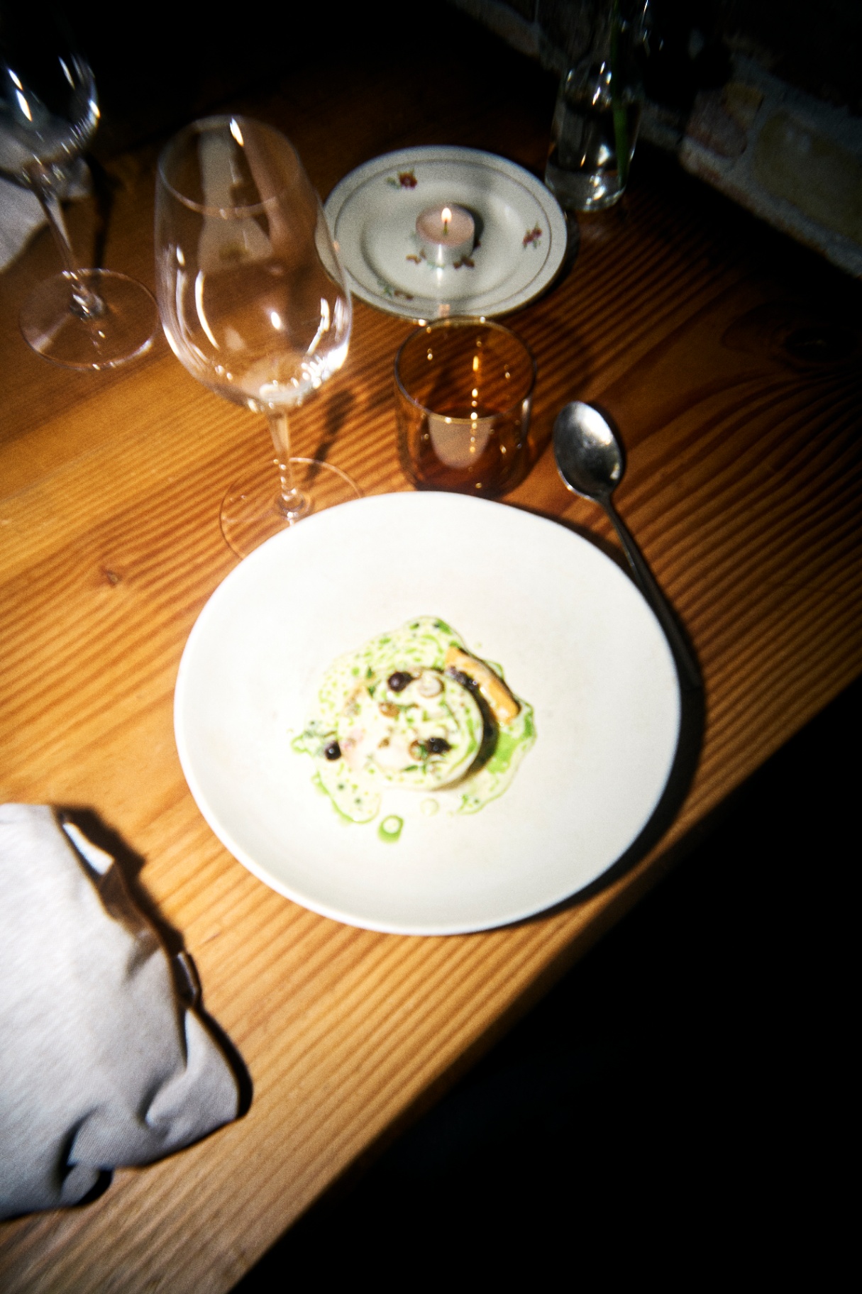 Anrettet ret på træbord med vinglas og stearinlys i spisesalen på Restaurant Grim